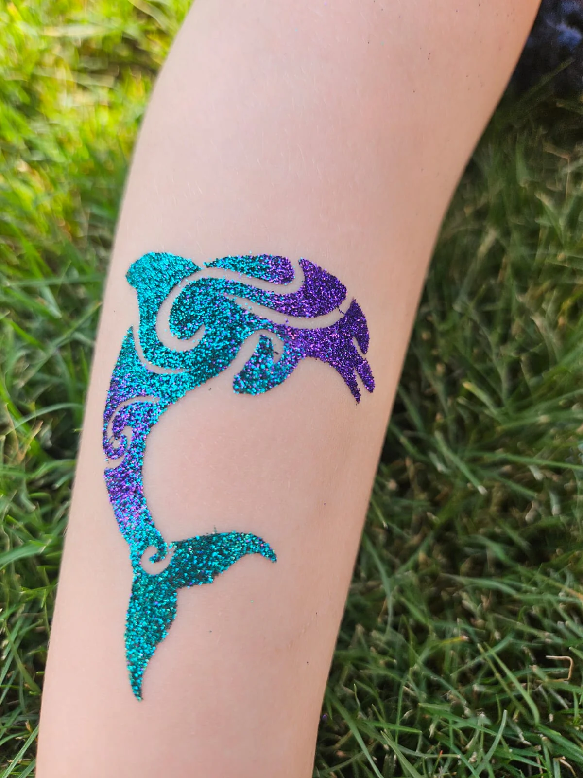 Detailed dolphin glitter tattoo by a Points Up artist